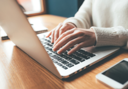 Das Bild zeigt einen Laptop, auf dessen Tastatur jemand tippt.