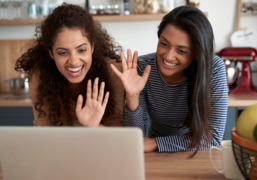 Das Bild zeigt zwei junge Frauen, die vor einem Laptop sitzen.