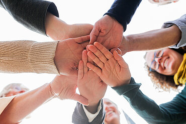 Auf dem Bild sieht man verschiedene Hände, die sich in der Mitte treffen.