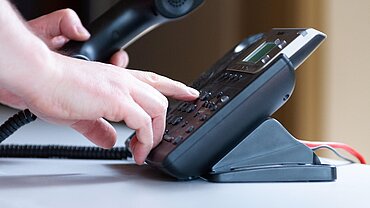 Telefon Eine Hand an einem Bürotelefon.