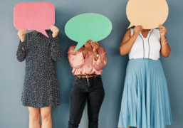 Das Bild zeigt drei Menschen, die jeweils eine bunte Sprechblase vor ihr Gesicht halten.