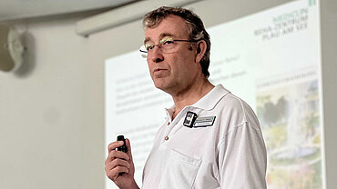 Dr. med. Jan Adolphsen Ein Mann vor einer Präsentation auf einer Leinwand.